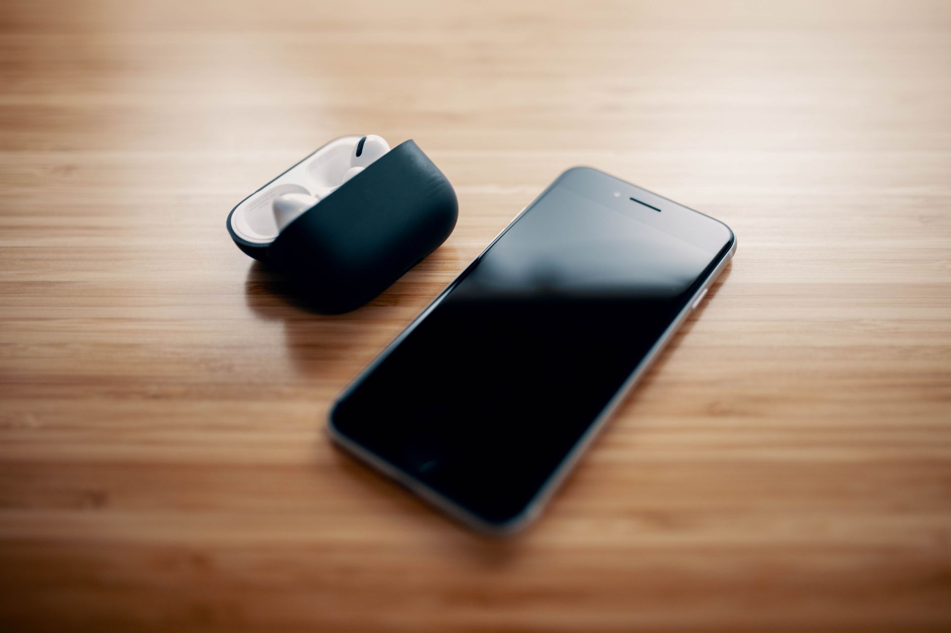 Móvil junto a un estuche de auriculares inalámbricos sobre una mesa