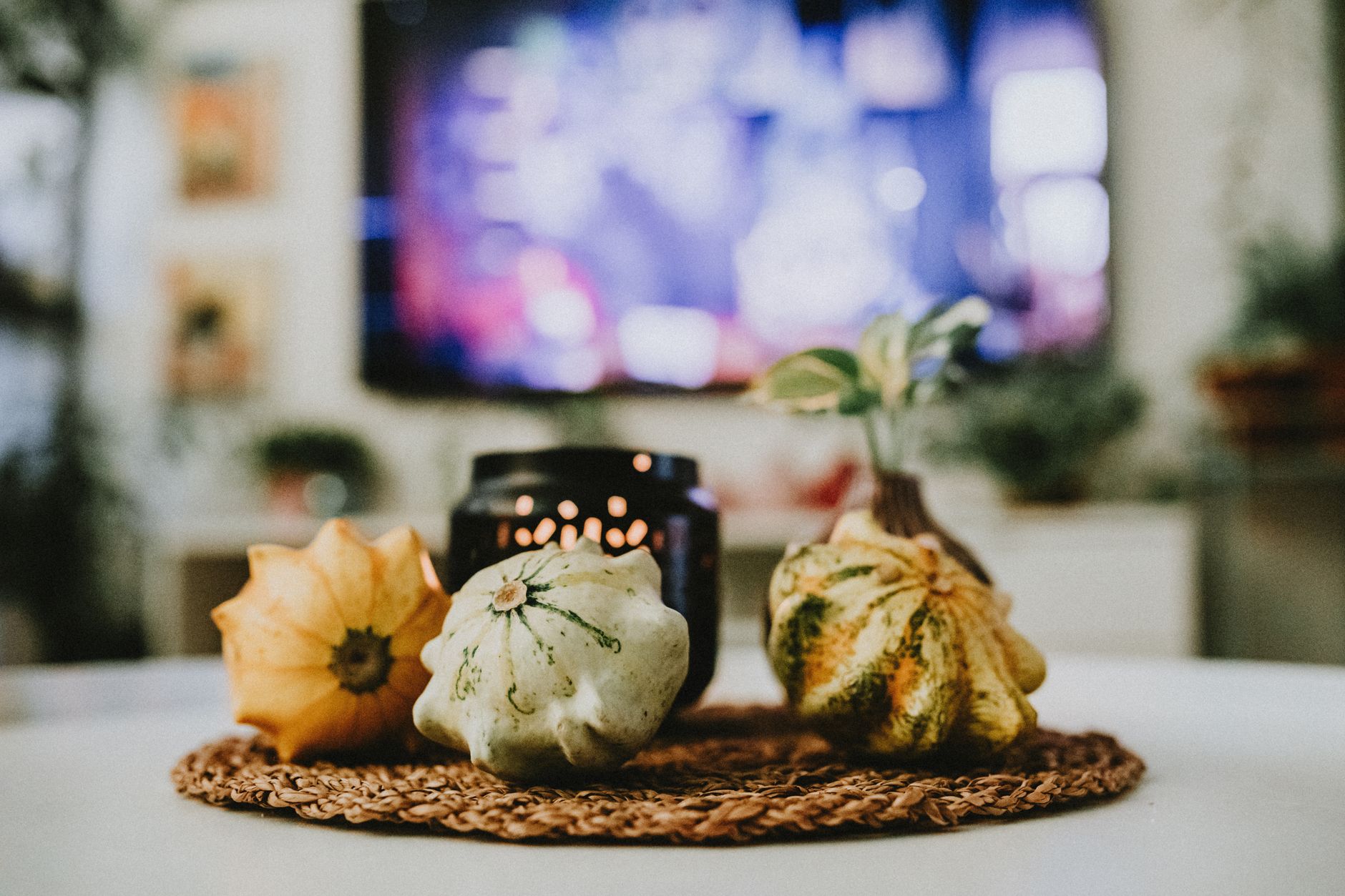 Centro de mesa con calabazas decorativas y vela en un salón, idea de decoración de Halloween para casa