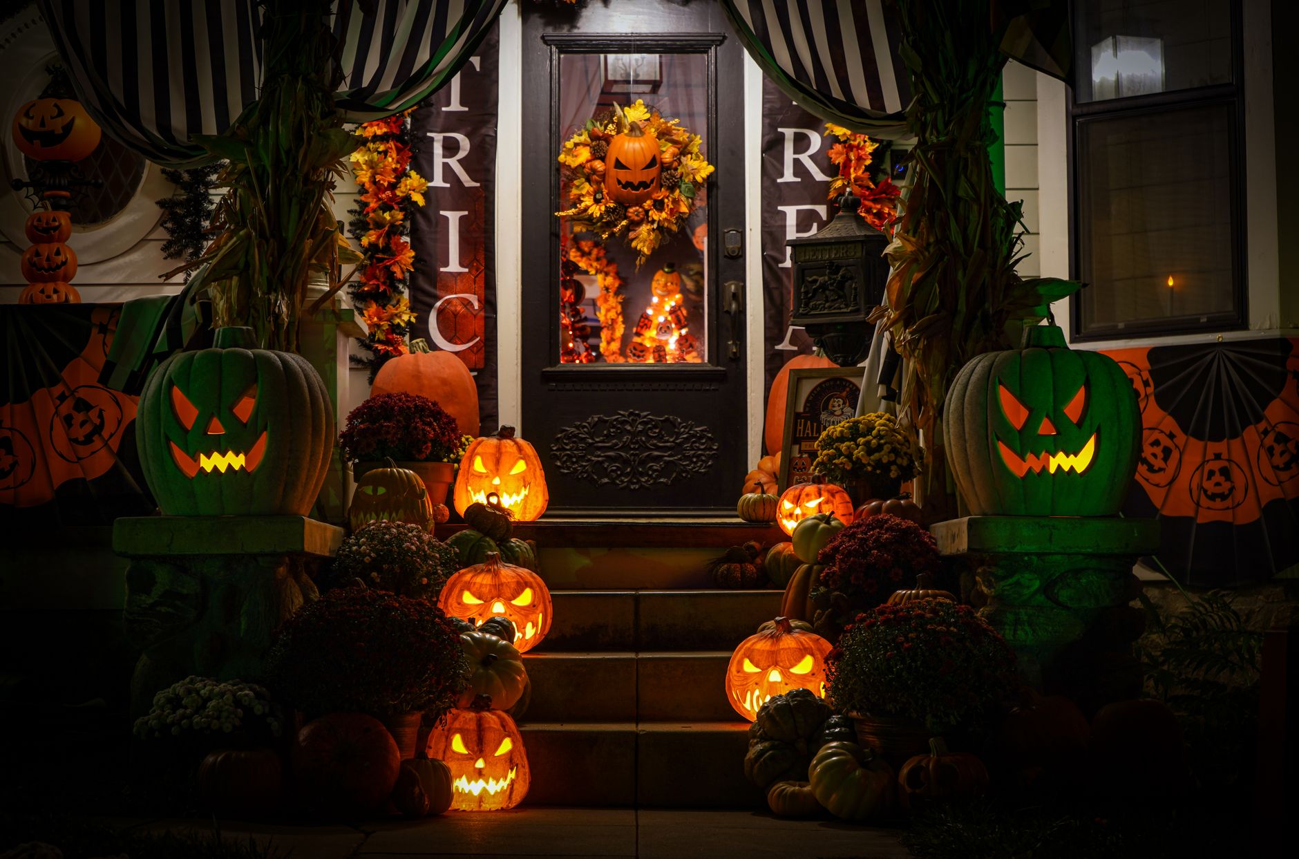 Decoración de Halloween en la puerta y la escalera de entrada: corona con calabaza, guirnaldas de hojas y calabazas iluminadas de noche