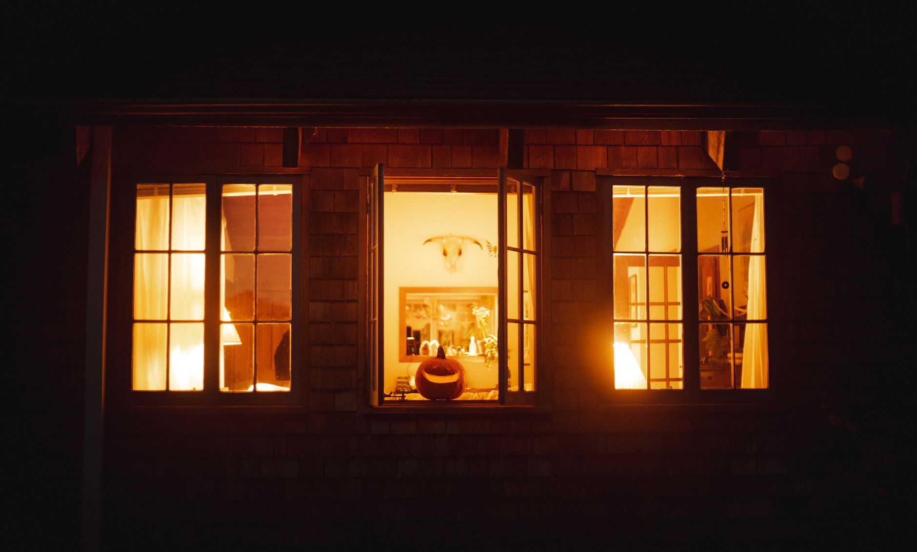 Ventana iluminada de noche con una calabaza de Halloween en el alféizar