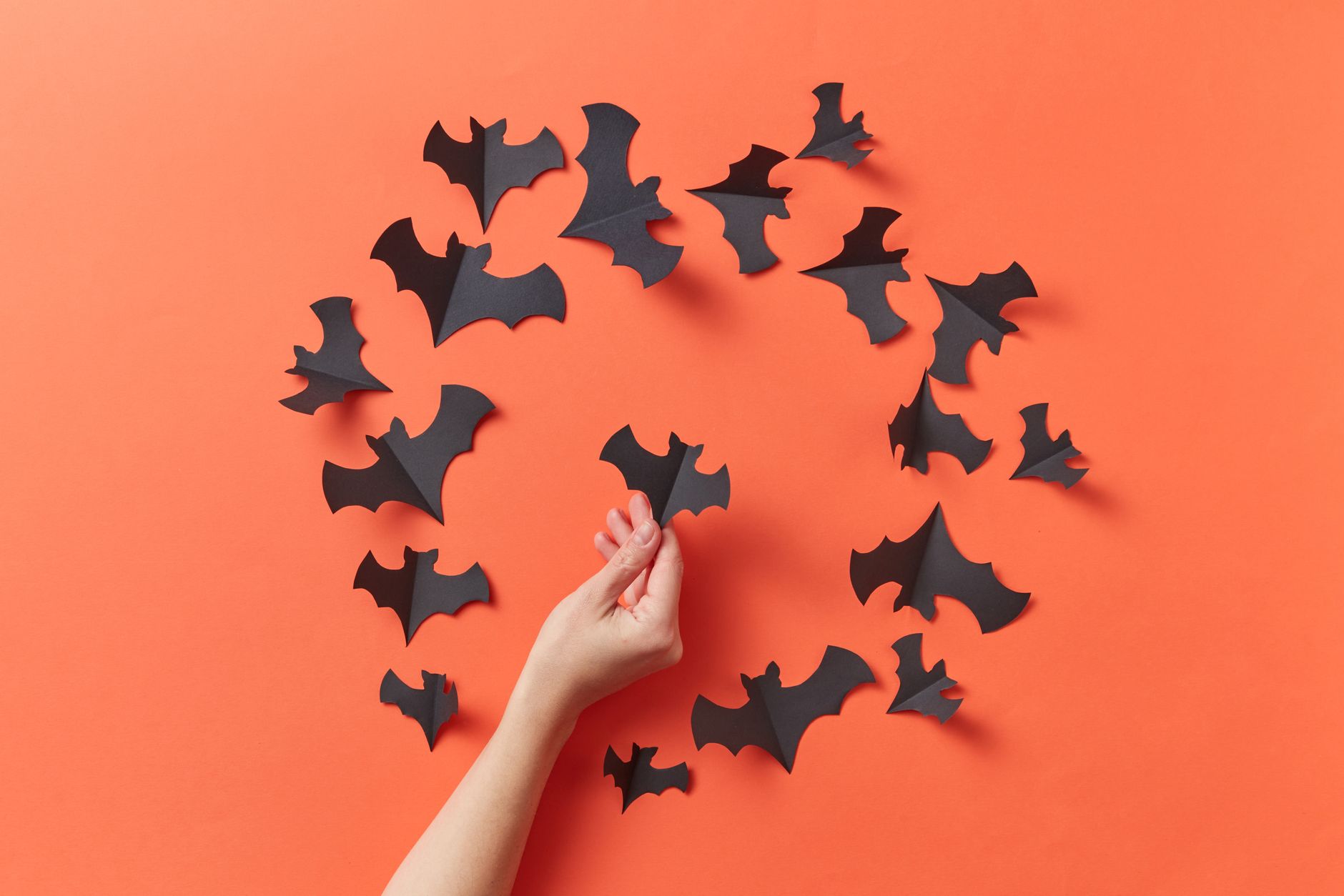 Murciélagos de cartulina negra para manualidades de Halloween infantiles sobre fondo naranja