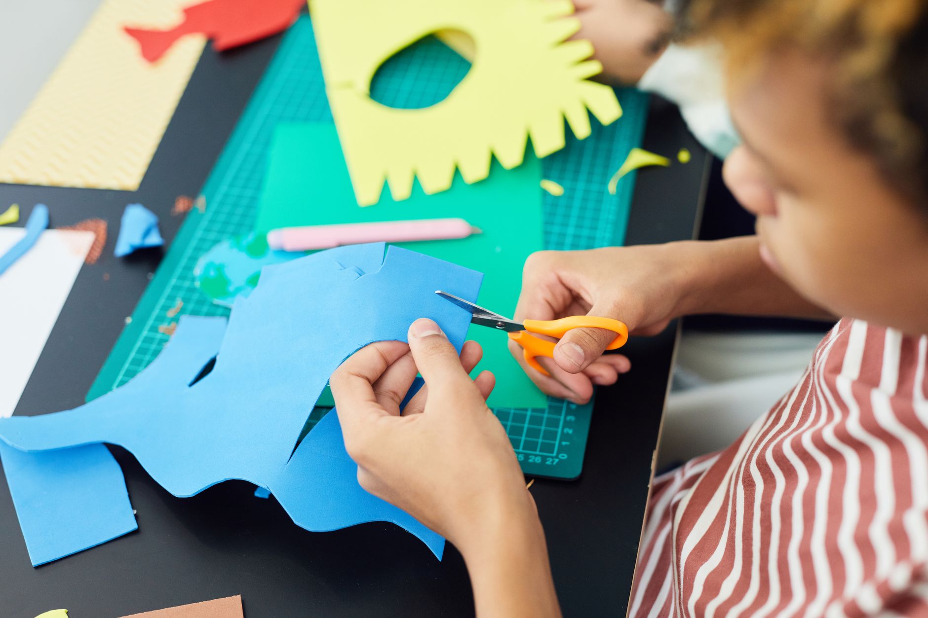 Niño recortando goma eva con tijeras infantiles en una manualidad