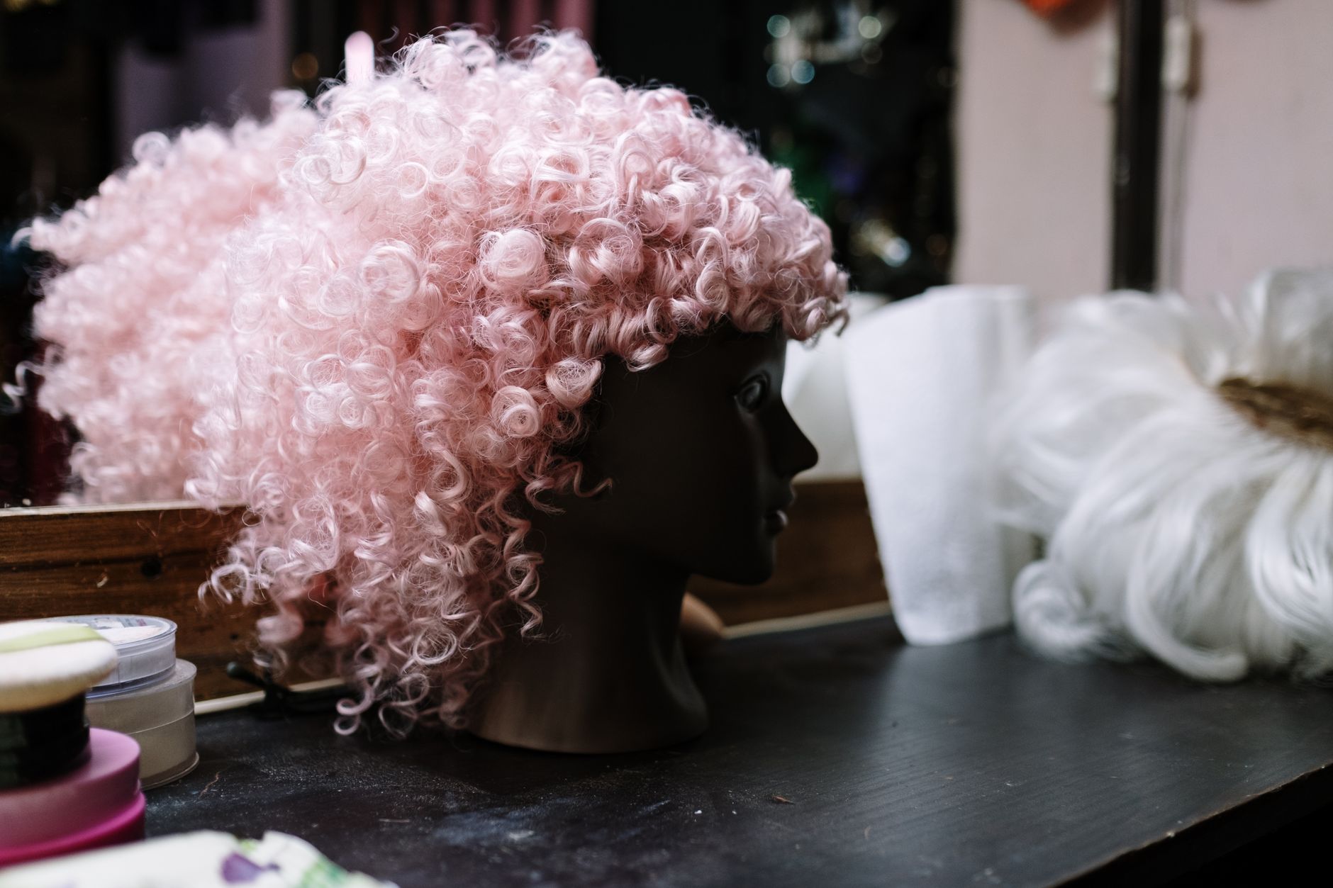 Peluca rizada rosa de disfraz sobre una cabeza de maniquí