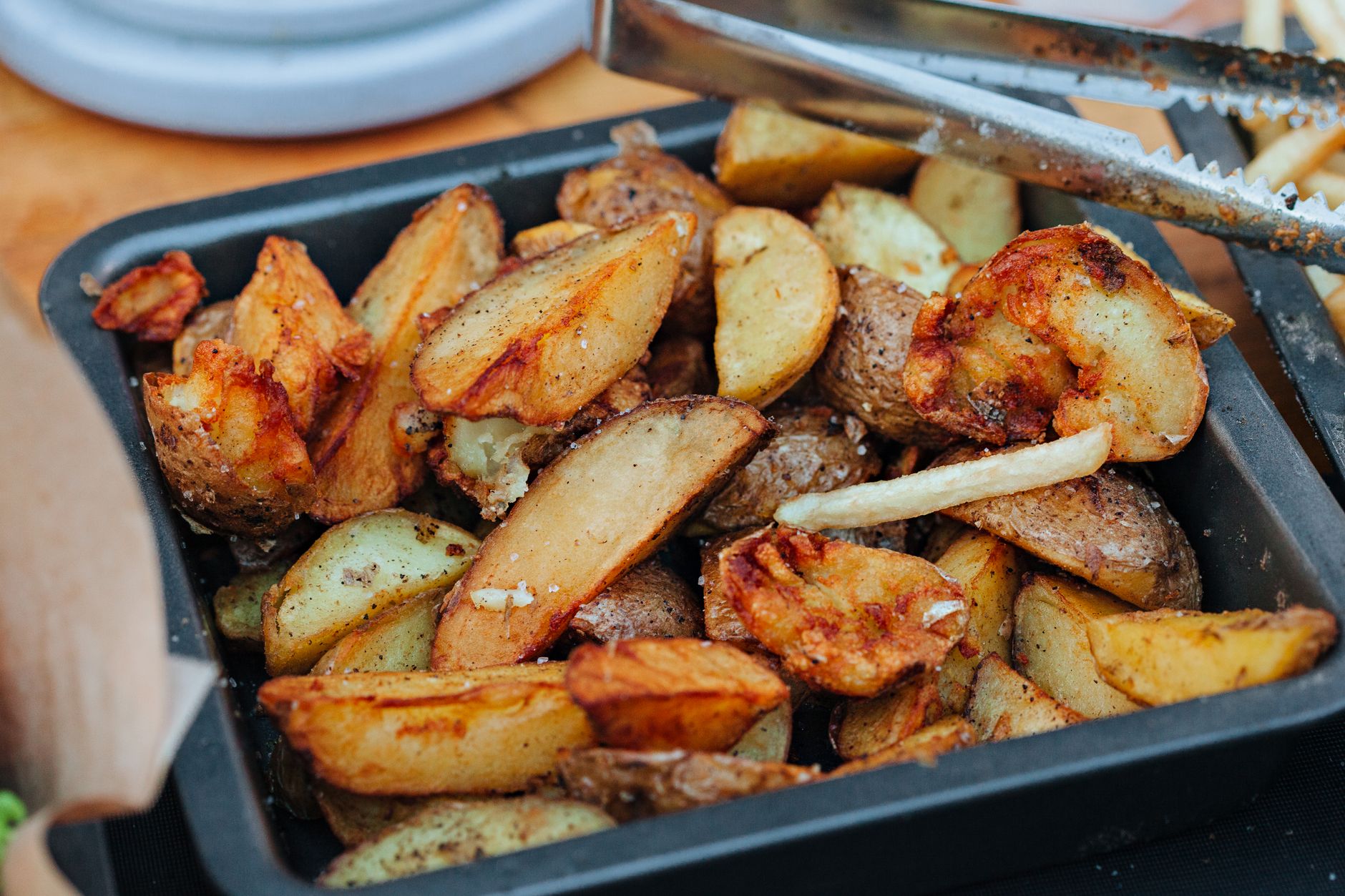Patatas gajo asadas y doradas en una bandeja oscura, ración familiar