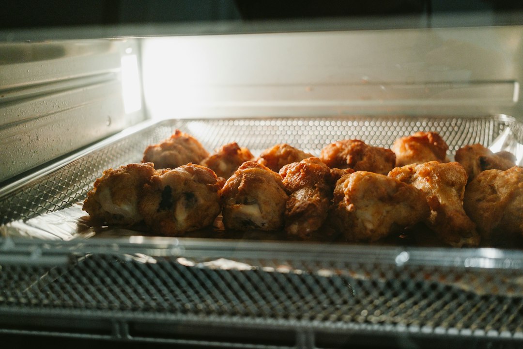 Alitas de pollo doradas sobre una bandeja de rejilla dentro de una freidora de aire horno